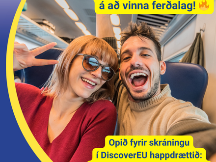 Tveir unglingar sitja glaðir í lestarsæti og halda í myndavélina fyrir sjálfu. Þau brosa og sýna 